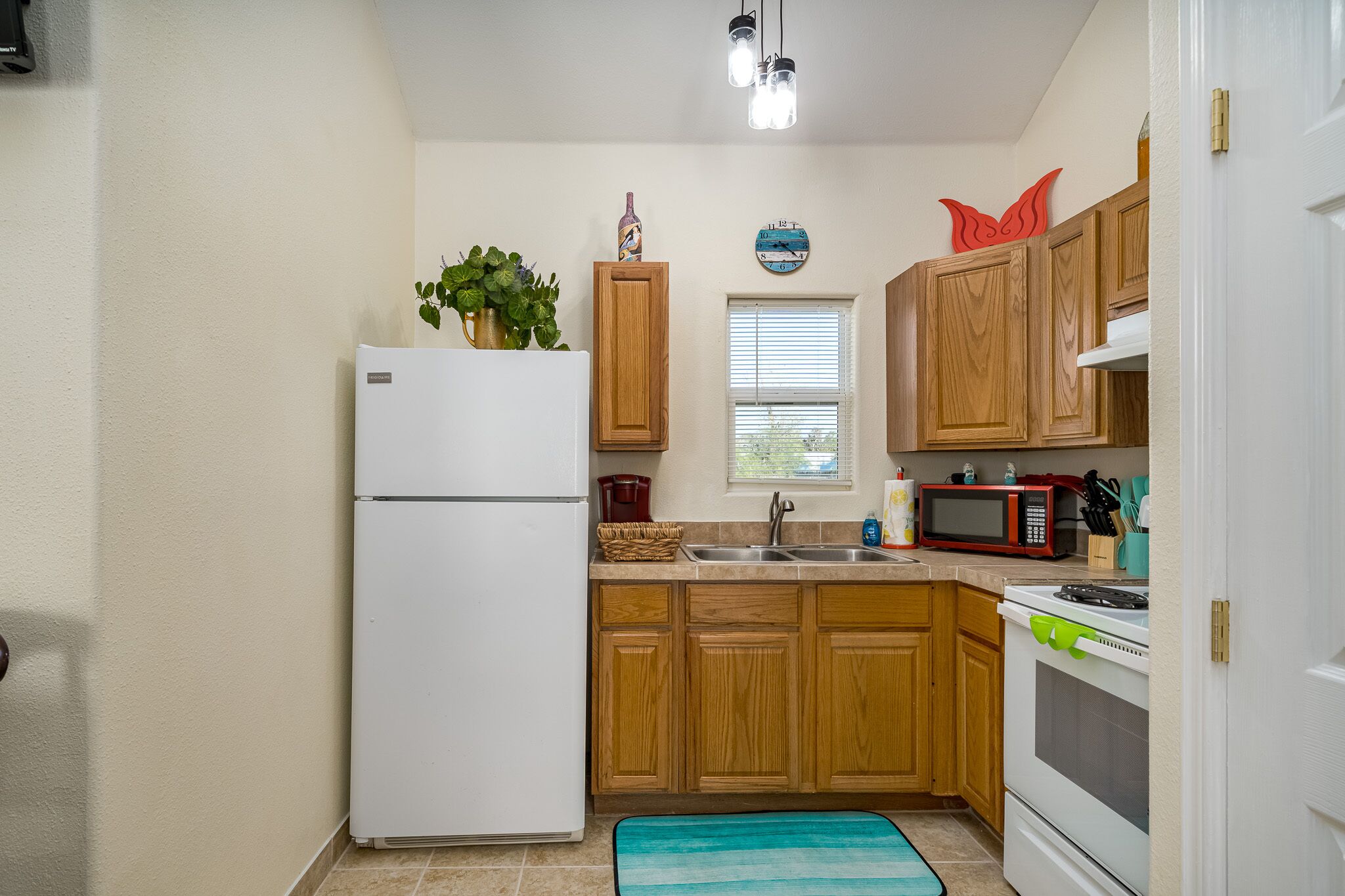 A compact kitchen with wooden cabinets, a white refrigerator, a microwave, and a stove.