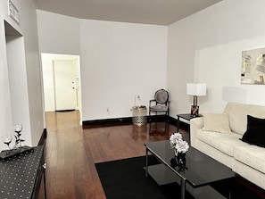 A spacious living room with a sofa, a coffee table, a chair, and a lamp. - Super Bowl 2023 condo !! (Sun City)
