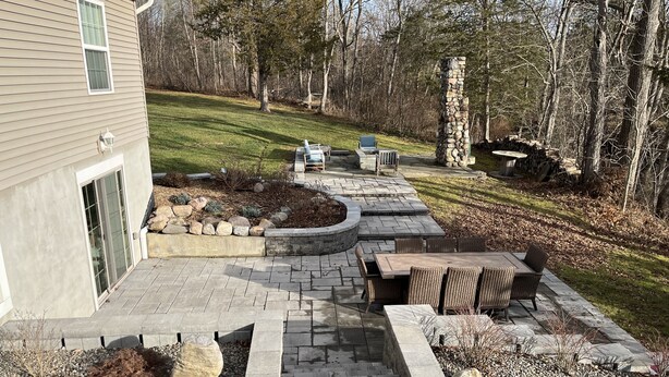 A patio with a stone fire pit, seating area, and a stone column.