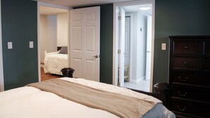 A bedroom with a bed, dresser, and a door leading to another room.
