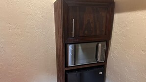 Eine Einbau-Mikrowelle und ein Kühlschrank in einem Holzschrank.