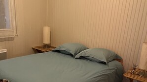 Une chambre à coucher avec un lit, une table de chevet, une lampe et une fenêtre.