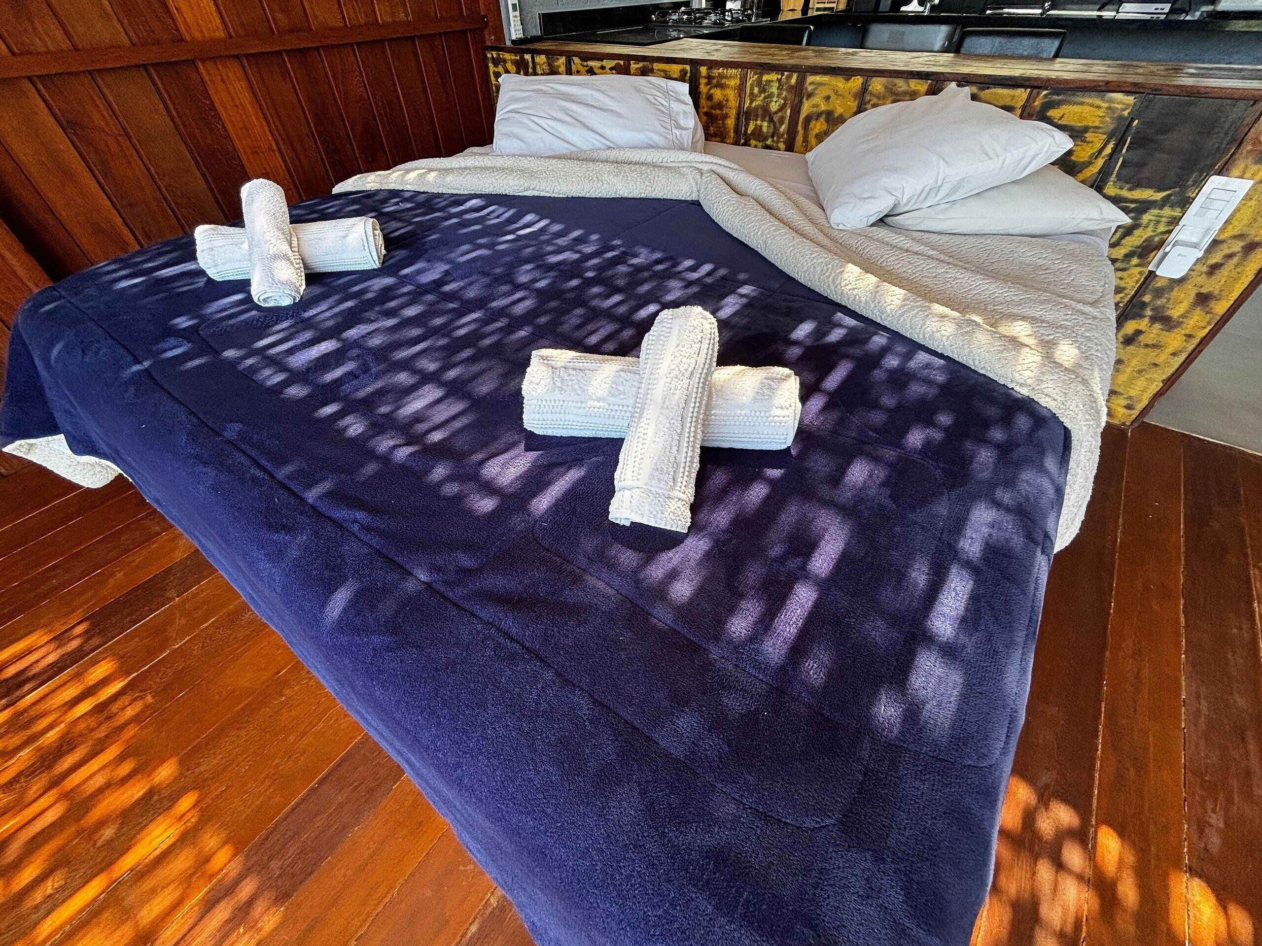 A room with a bed covered in a dark blue blanket, a wooden floor, and a wooden headboard.