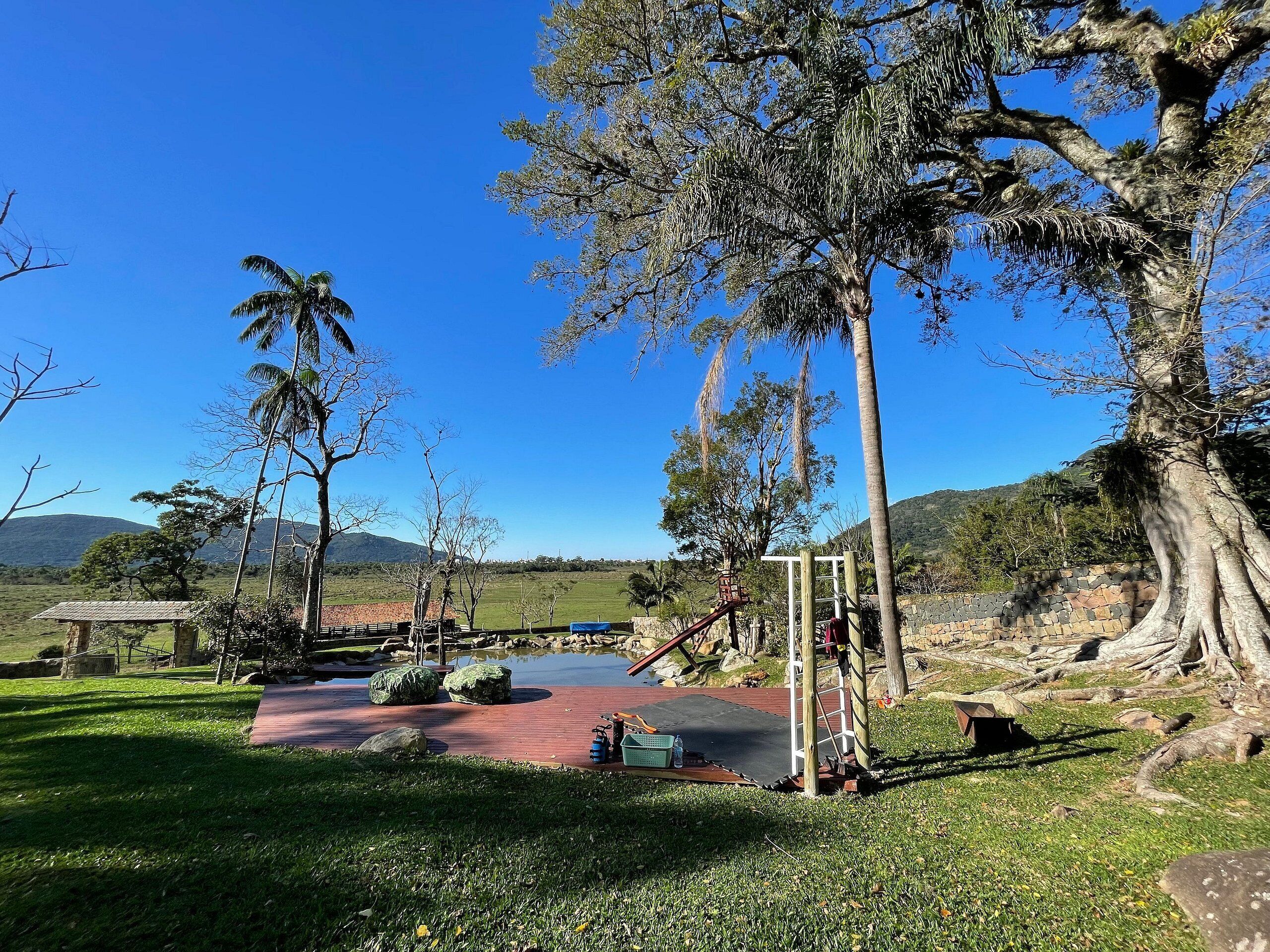 Ein Park mit einem Spielplatz, einem Teich und einer Steinmauer.