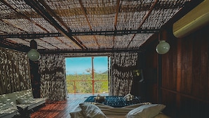 A room with a large window, a bed, a sofa, and a wooden floor. - Casa de Vidro - Hospedar com Propósito (Florianópolis)