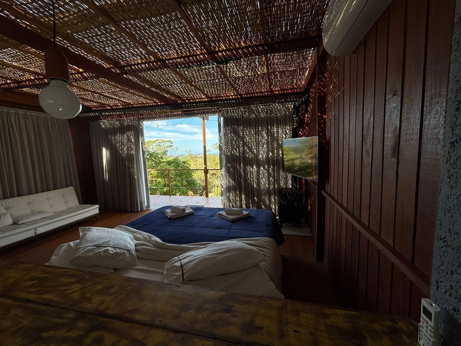 Une chambre avec un lit, un canapé, une télévision et une vue sur la verdure.