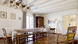 A dining area with a long wooden table, chairs, and a chandelier. - Villa PIERROT      . (La Flotte)