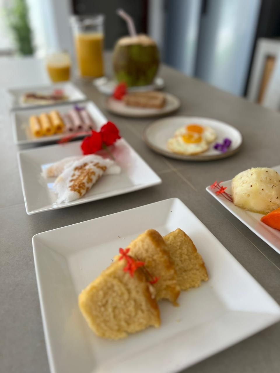 A breakfast buffet with various dishes including eggs, pastries, and a fruit drink.