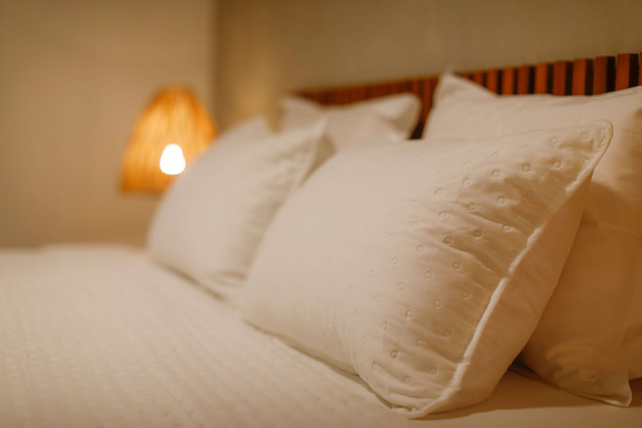 A neatly made bed with white pillows and a striped headboard.