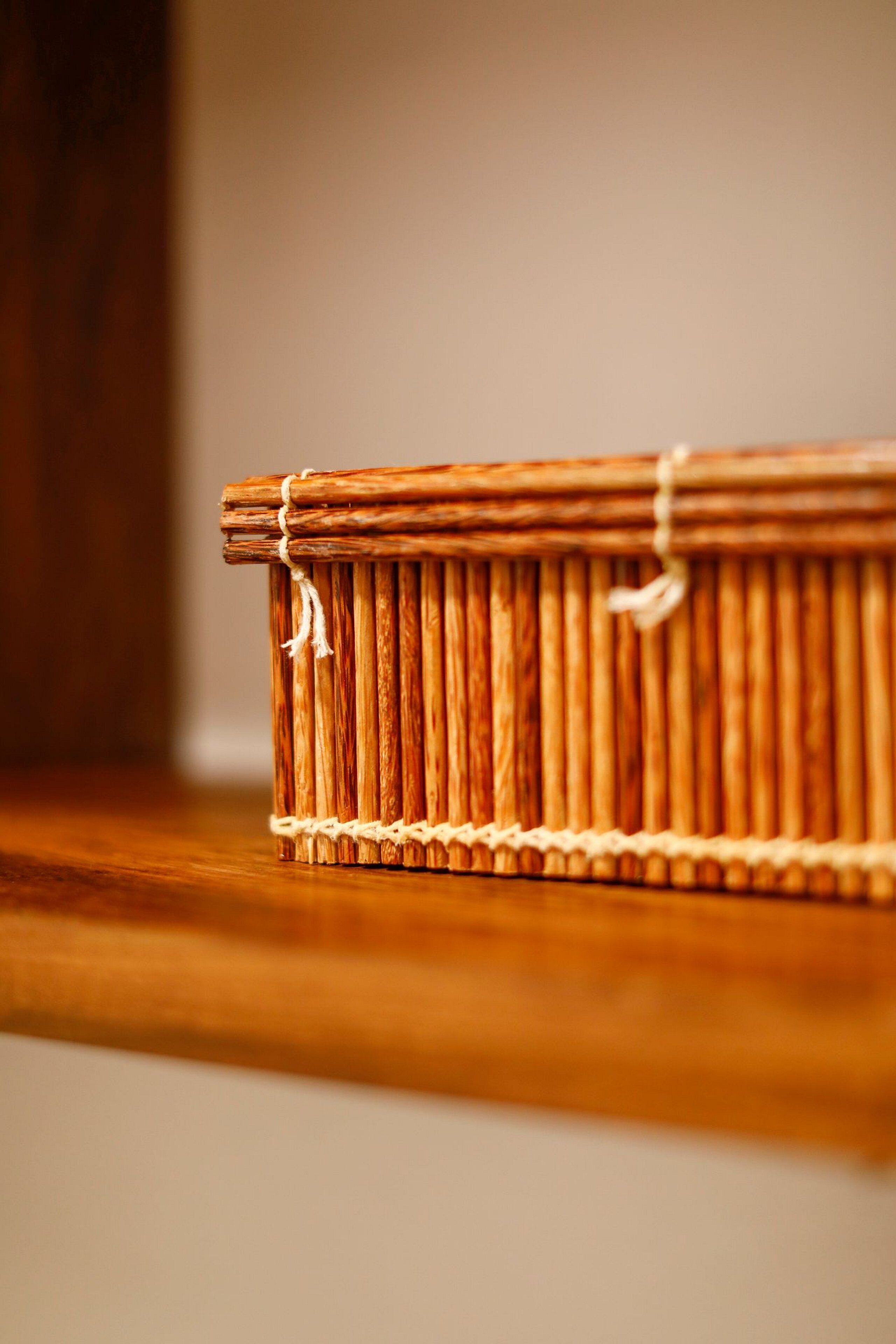 A woven basket tied with a string, placed on a wooden surface.
