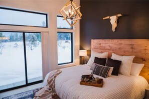 Relax in a spacious bedroom with a large bed, wooden headboard, and stunning views of the outdoors.