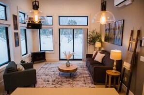 Relax in this stylish living room with a round coffee table, dark sofa, and matching armchair.