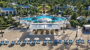 A resort with a central pool, sun loungers, and a covered dining area. - Luxury resort with beach, pool, many amenities (Cruz Bay)