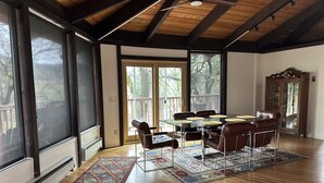 A spacious dining area with a wooden table and chairs, large windows, and a view of the outdoors. - RustRidge House, two bedroom two bath home (St Helena)