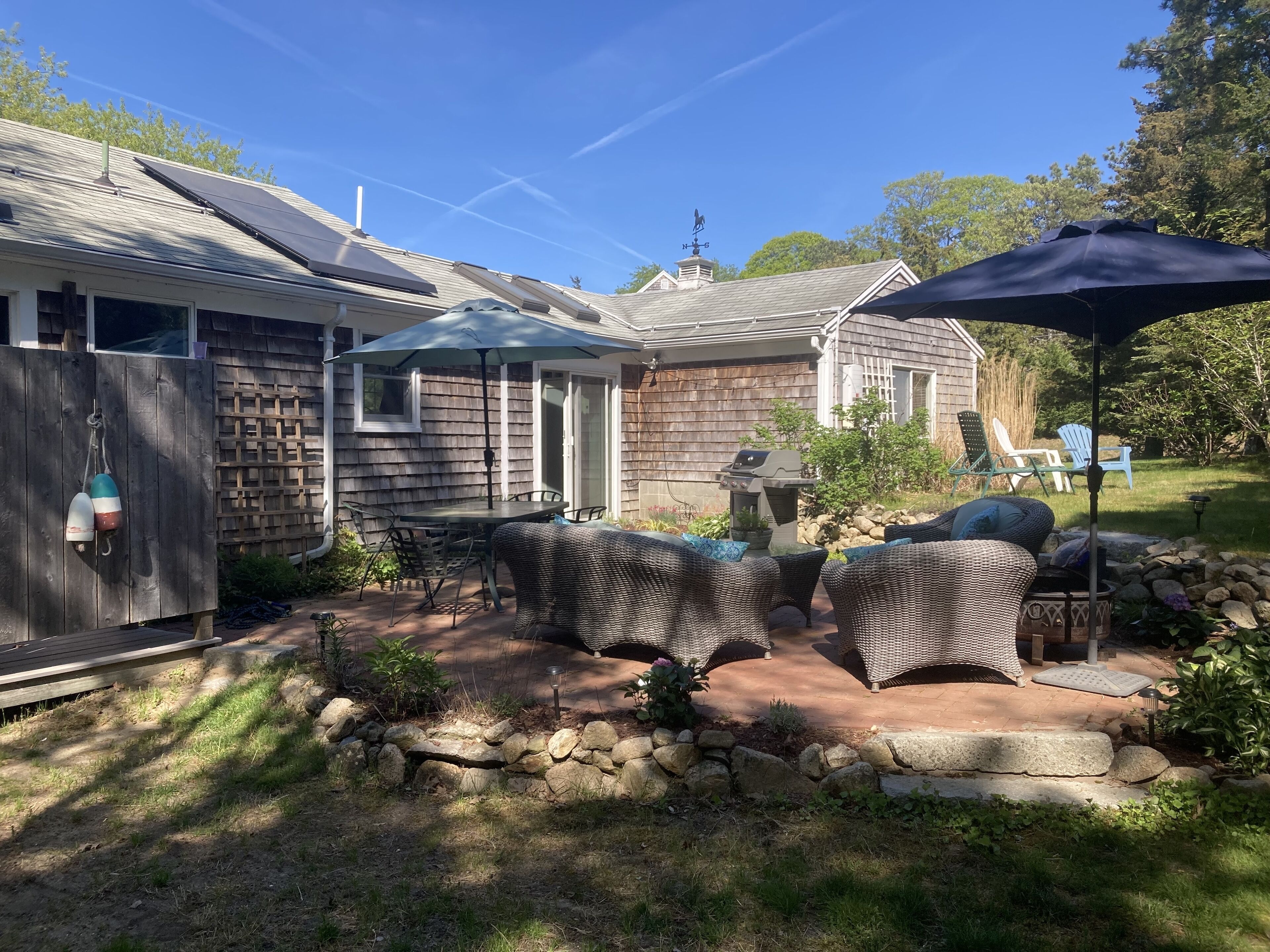 A patio with outdoor furniture, a grill, and a covered area with an umbrella.