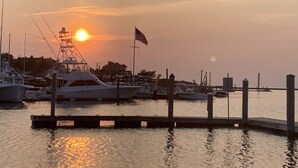 Un puerto deportivo con barcos amarrados, cielo despejado y una puesta de sol.