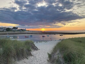 A beach with boats, a sunset, and houses in the background. - Rates just lowered for last week of July and Aug with 5 night min accepted. (Dennis)