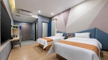 Quarto de hotel com duas camas, uma escrivaninha e um pequeno espaço para sentar.