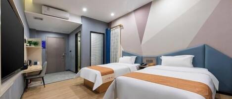 Habitación de hotel con dos camas, un escritorio y una pequeña zona de estar.