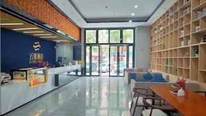 A hotel reception area with a modern design, featuring a reception desk, seating area, and a bookshelf. - U-FREE Hotel (Dongguan Xiegang Square) (Dongguan)