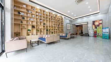 A hotel lobby with a large bookshelf, seating area, and a reception desk.
