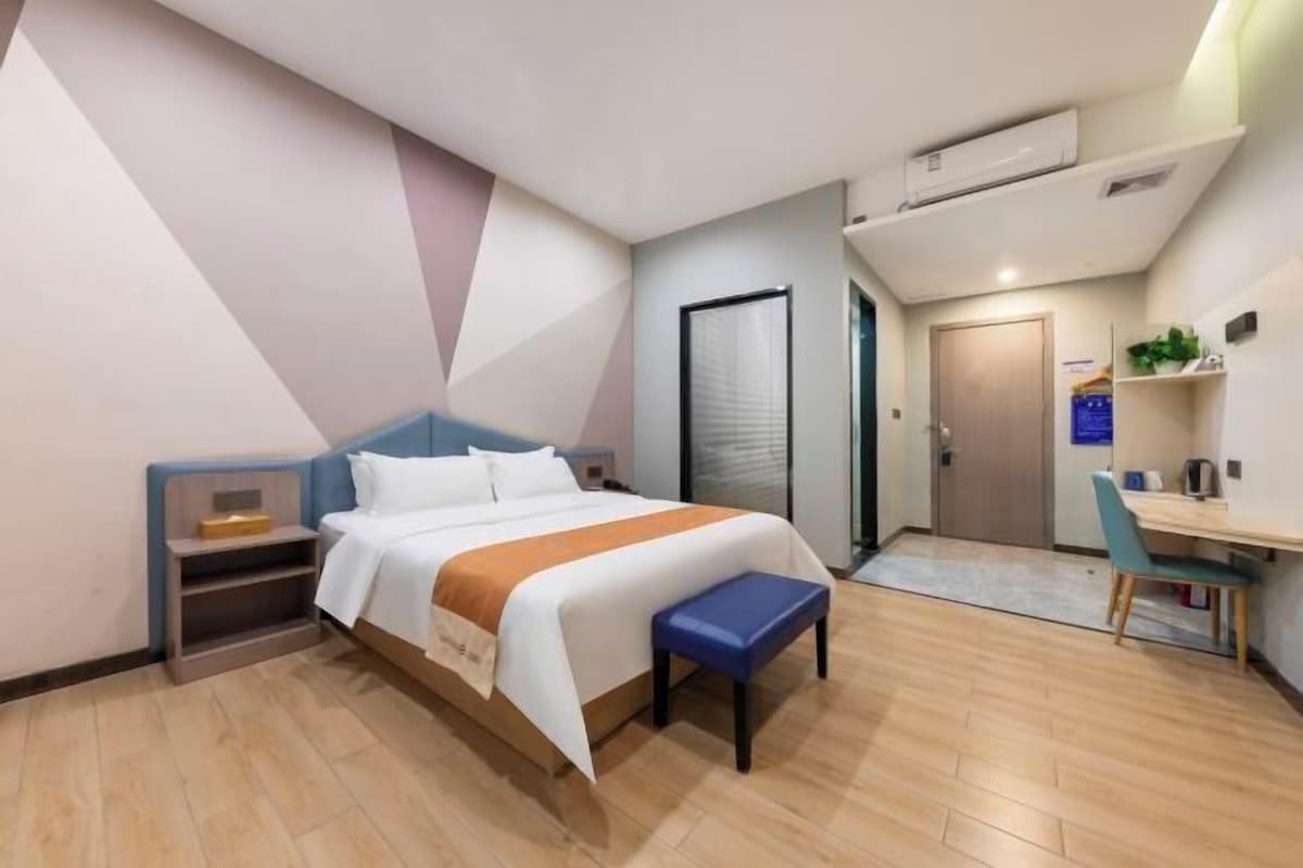 Ein Hotelzimmer mit einem Bett, einem Schreibtisch, einem Stuhl, einer Bank und einer Tür.