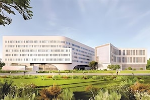 A modern building with a curved facade, a central courtyard, and a well-maintained garden. - U-FREE Hotel (Dongguan Xiegang Square) (Dongguan)