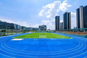 A blue running track with a goalpost, surrounded by modern buildings and a clear sky. - U-FREE Hotel (Dongguan Xiegang Square) (Dongguan)