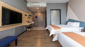 A modern hotel room with a large flat-screen TV, a desk with a chair, two beds with white bedding, and a blue bench. - U-FREE Hotel (Dongguan Xiegang Square) (Dongguan)