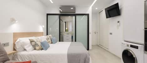 Een moderne slaapkamer met een bed, een wasmachine en een televisie.