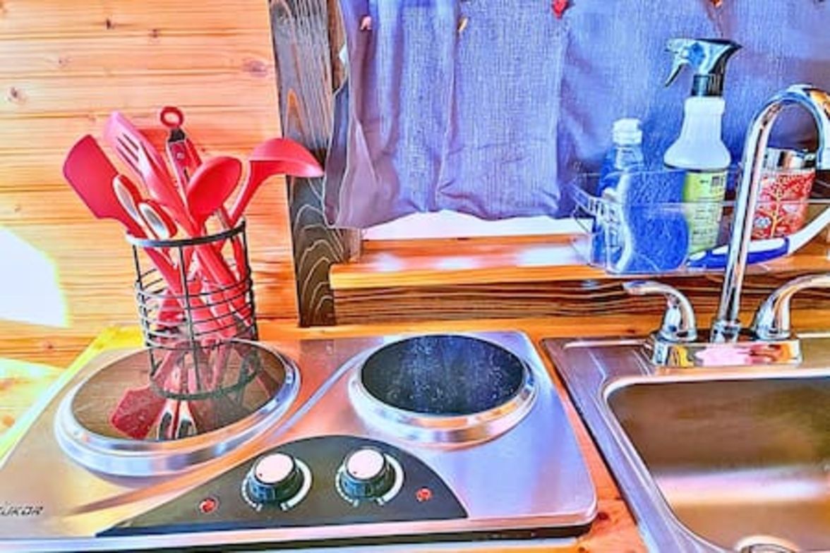 Una cocina con estufa, pileta y utensilios.