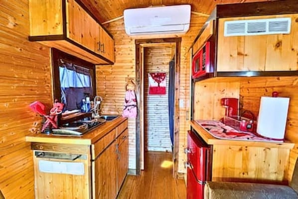 A wooden cabin interior with a kitchen area, a dining table, and a microwave.