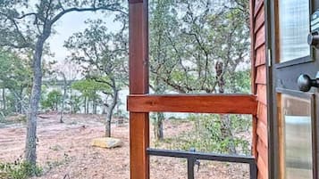 Une structure en bois dotée d’une porte en métal, entourée d’arbres et bordée d’un paysage aride.