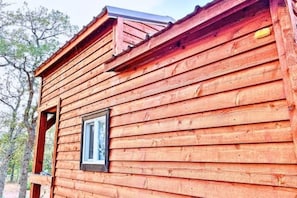 A wooden cabin with a pitched roof, a window, and a visible door.