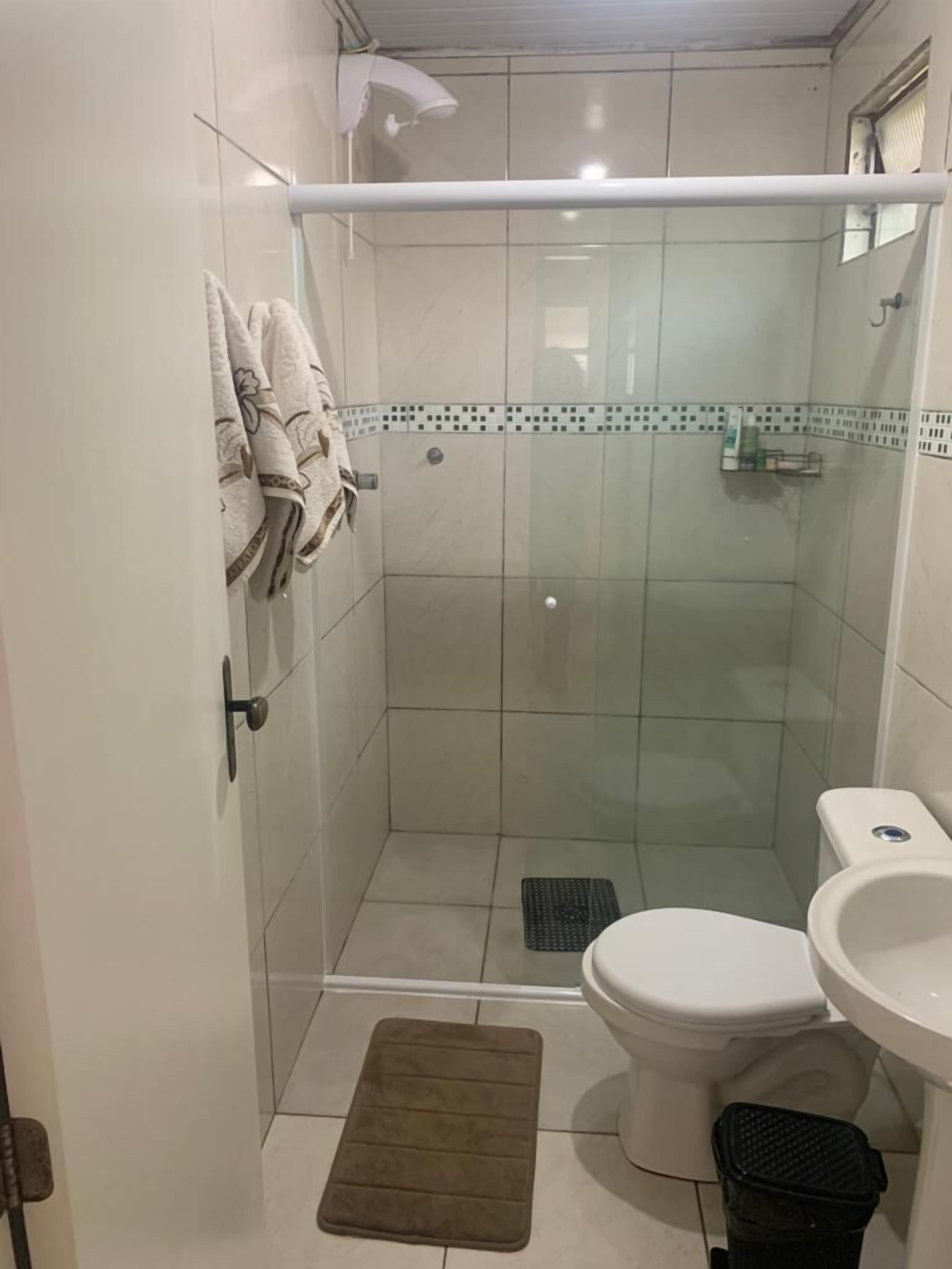 A small, enclosed shower area with a glass door, a toilet, and a sink.