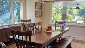 Un espace repas comprenant une table en bois, six chaises, un banc et un luminaire suspendu.