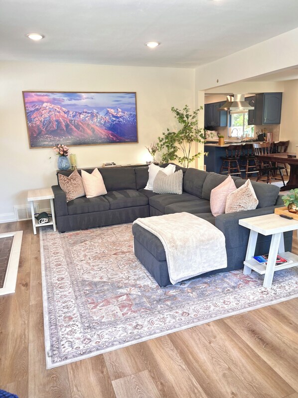 A living room with a sectional sofa, a coffee table, a rug, and a large painting on the wall.
