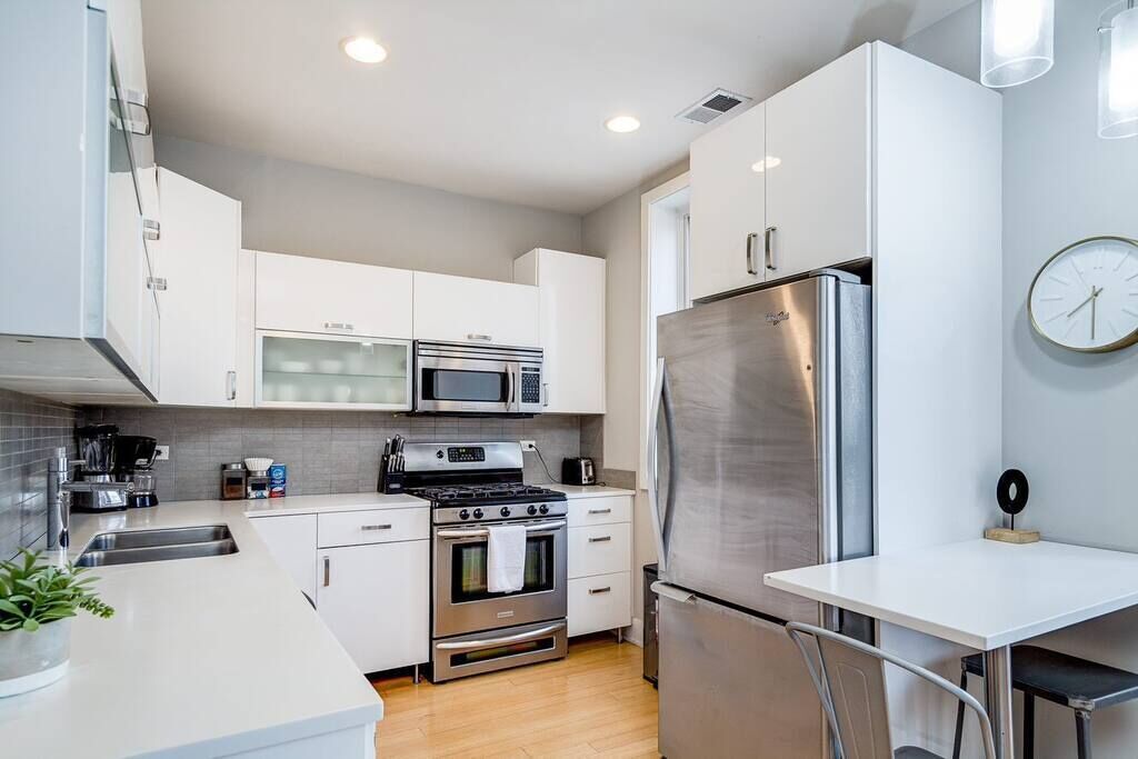 A modern kitchen with white cabinets, stainless steel appliances, a microwave, oven, and a refrigerator.