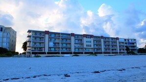 Un hotel de varios pisos con balcones, situado en una playa de arena.