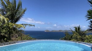 Piscina azul cristalina con vista al océano y a islas distantes.