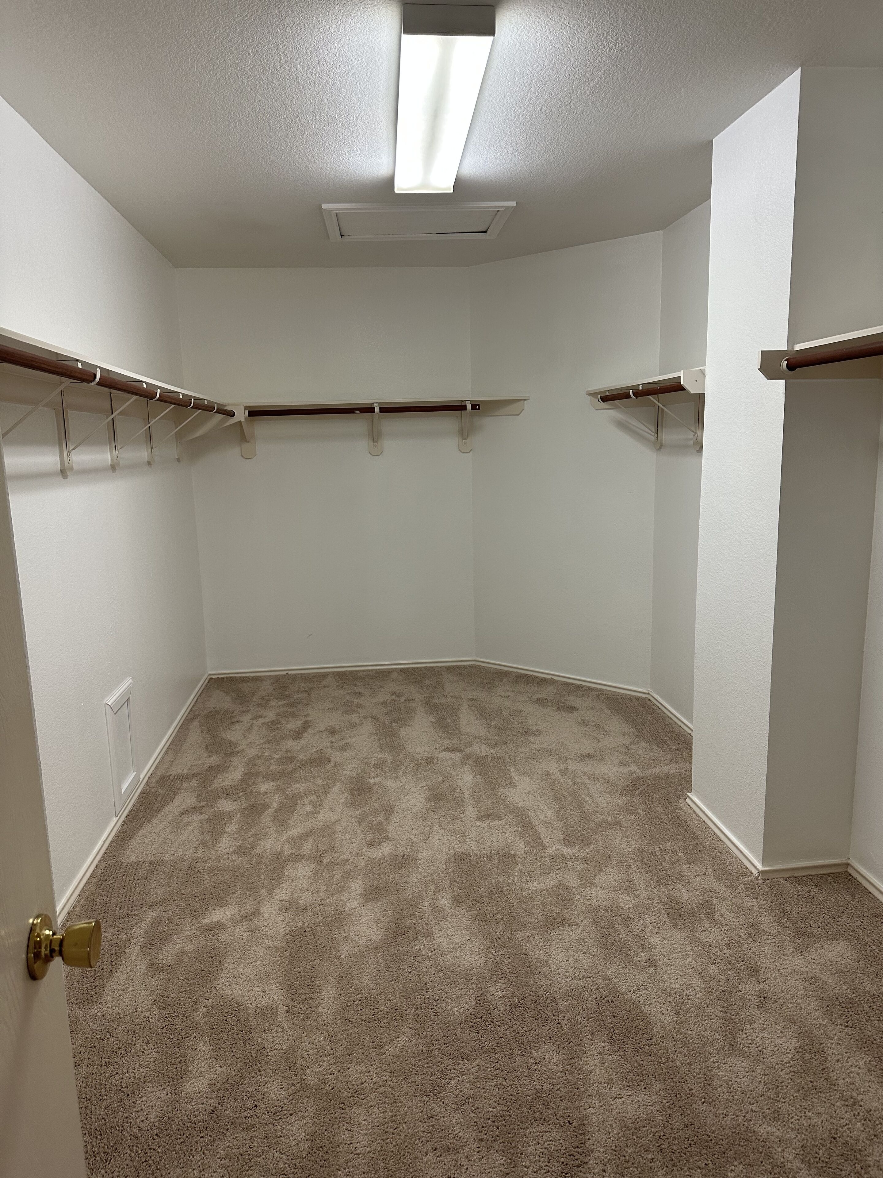 Une pièce avec un tapis beige, des murs blancs et des étagères intégrées.