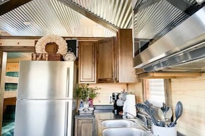 A compact kitchen with a stainless steel refrigerator, wooden cabinets, and a built-in oven. - 6 Tiny Town + Monthly + Utilities + Comfy Stay (Hico)