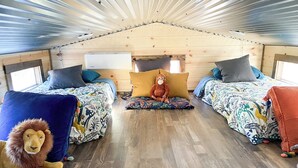 A cozy interior with two beds, a plush lion toy, and a monkey plush on a pillow. - 6 Tiny Town Hico - Big Texas Ranch Experience (Hico)
