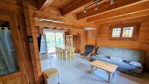 A wooden cabin interior with a dining area, a sofa, and a table.