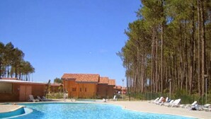 A pool area with lounge chairs and a building with a tiled roof.