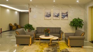 A lobby with a sofa, two armchairs, a coffee table, and a potted plant. - Huangjia Xiyan Hotel (Taishan)