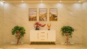 A lobby with a white console table, three framed landscape paintings, and two potted plants. - Huangjia Xiyan Hotel (Taishan)
