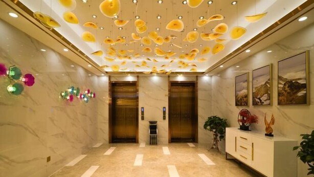 A modern lobby with marble flooring, two elevators, a reception desk, and decorative ceiling lights. - Huangjia Xiyan Hotel (Taishan)