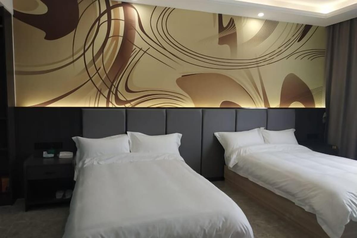 A hotel room with two beds, a nightstand, and a wall with abstract art.