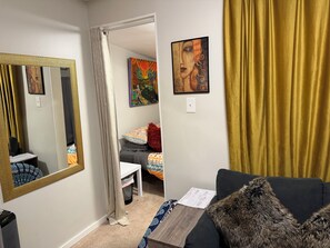 A room with a large mirror, a painting, a sofa with a fur throw, and a curtain. - Book one week or more and get 10% discount
Stylish 2 BR Suite in West Seattle!
 (Seattle)